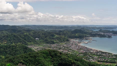 Wide-open-timelapse-over-small-ocean-town-with-rolling-hills,-ocean-and-clouds