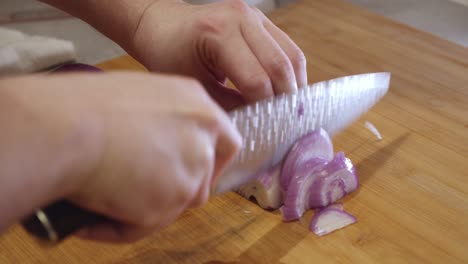 Slicing-onion-with-sharp-knife-on-a-cut-board