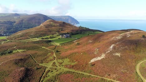 Rural-Welsh-heather-covered-mountain-hillside-valley-ocean-coastline-aerial-orbit-right-view