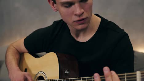 Caucasian-guy-in-black-T-shirt-playing-on-guitar.-Close-up-of-male-hands-playing-on-acoustic-guitar.-Professional-guitarist-musician-playing-solo-on-guitar.-Close-up-of-fingers-of-man-musician-and-strings.-Slow-motion