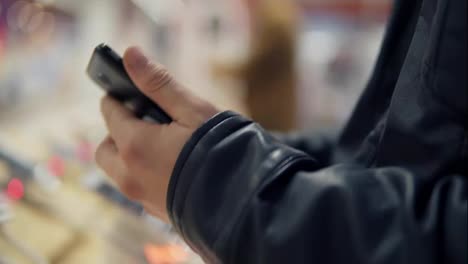 Closeup-view-of-a-young-man's-hands-choosing-a-new-mobile-phone-in-a-shop.-He-is-trying-how-it-works