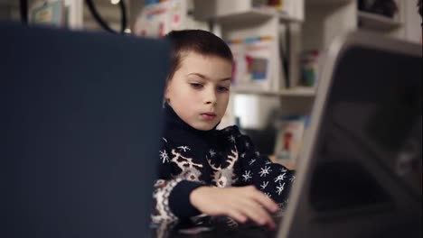 Portait-footage-of-a-little-boy-wth-big-blue-eyes-trying-to-learn-how-to-use-laptop.-Educational-process.