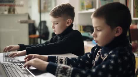 Footage-of-two-little-boys-trying-to-type-something,-learning-how-to-use-laptops.-Alternative-programming-education-for-children.