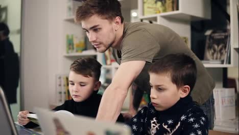 Footage-of-two-boys-and-their-young-male-programmer-teacher-in-a-classroom-learning-how-to-use-laptop.-Alternative-education-for-children.
