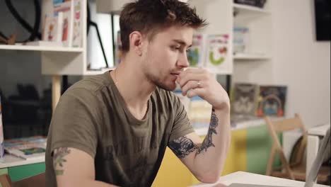 Attractive-sexy-programmer-with-tattooes-on-his-arms-thinking-hard-about-something.