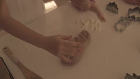 Closeup-young-girl-hands-kneading-dough-on-a-white-table-in-kitchen.-Healthy-food,-childhood,-family,-handmade,-hobby,-bakery-concept.-High-angle-view