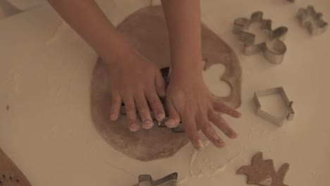 Top-view-of-child's-hands-making-traditional-Christmas-cookies.-Raw-dough-and-cutters-for-holiday-cookies-on-the-white-table---making-fir-tree-shaped-cookie