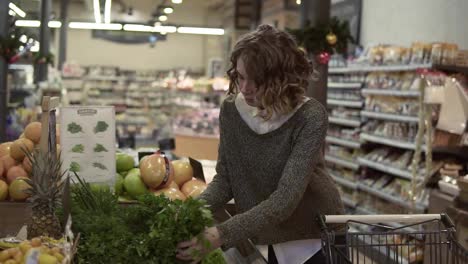 Young-woman-buying-Ooganic-food-in-supermarket.-Female-taking-green-fresh-parsley-in-grocery-store.-Choosing-good-pale.-Slow-motion.-Healthy-Lifestyle-Concept
