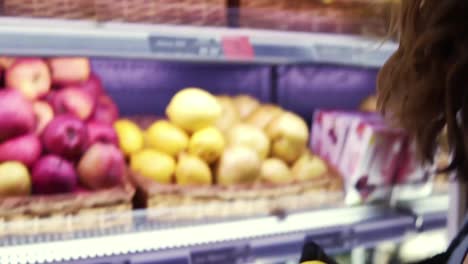 Close-up-of-female-worker-in-black-gloves-stocking-the-lemons-in-supermarket.-Young-employee-at-work.-Curly-female-arranging-lemons-on-shelf.-Slow-motion