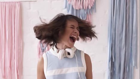 Slow-motion-footage-of-a-yong-brunette-girl-having-fun,-shaking-her-head-and-shouting.-Indoors