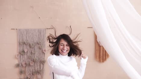 Cute-young-beautiful-girl-jumping-on-the-bed-in-a-white-shirts-and-jumper.-Slow-motion