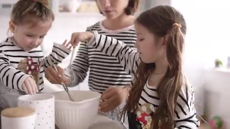 Girl-with-long-brunette-hair-and-her-sister-are-helping-their-mother-on-the-kitchen