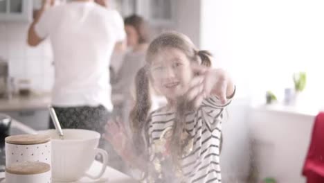 Little-girl-with-long-brunette-hair-throws-flour-on-the-kitchen