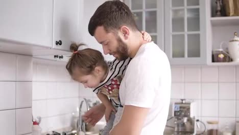 Dad-holds-a-small-daughter-in-his-arms-on-the-kitchen