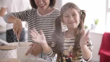 Daughter-throws-flour-and-mother-is-kneading-the-dough-on-the-kitchen