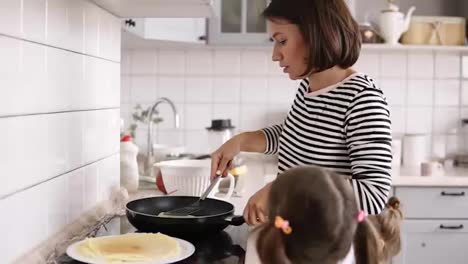 Mutter-Kocht-Pfannkuchen-In-Der-Küche,-Töchter-Bleiben-In-Der-Nähe
