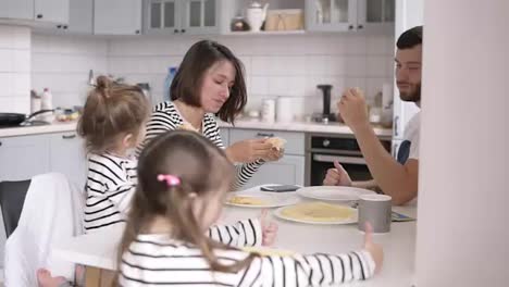 Schöne-Junge-Familie-Mit-Zwei-Kindern,-Die-Zu-Hause-Gemeinsam-Frühstücken.-Pfannkuchen-Essen-Und-Spaß-Haben