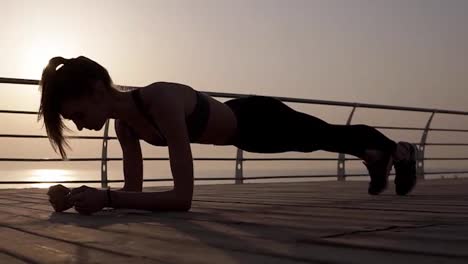Young-female-silhouette-doing-plank-exercise-on-a-seaside.-Strong-body.-Dusk.-Morning-sunrise