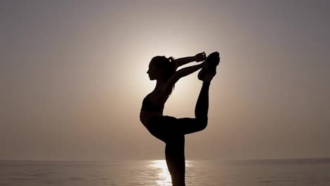 Outstanding-womans-silhouette.-Front-view-of-a-girl-stretching-and-practicing,-Doing-a-vertical-twine,-bends-her-leg.-Sunrise