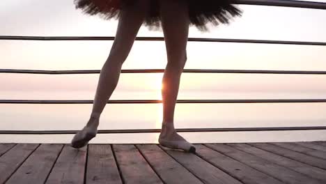 Close-up-of-a-beautiful-ballerina's-legs.-A-girl-stretches-her-leg-muscles,-bending-her-feet.-In-pointe-shoes.-Morning-on-the-seaside