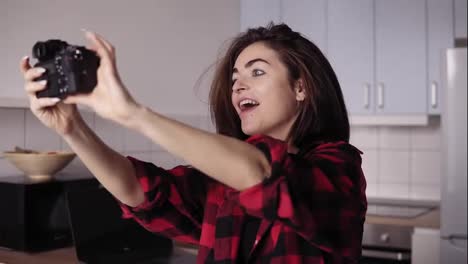 Young-attractive-brunette-girl-is-making-funny-face-trying-to-take-a-selfie-with-professional-photo-camera.
