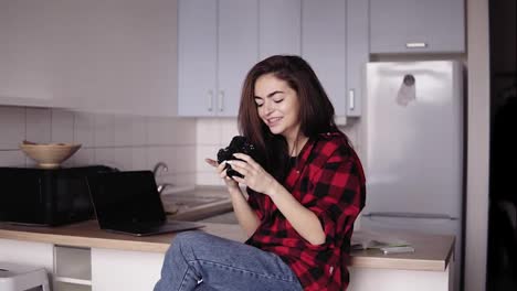 Attractive-girl-in-her-20's-is-smiling-while-looking-through-the-photos-on-her-camera.