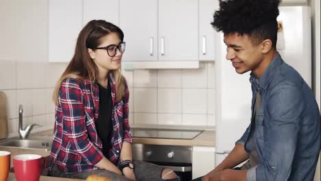 Cute-romantic-couple-sitting-in-the-kitchen-having-a-funny-conversation,-smiling-and-laughing.