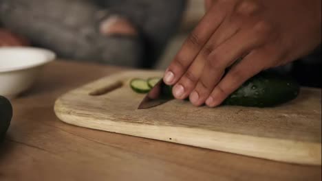 Close-up-slow-motion-footage-of-a-young-attractive-joyful-mulatto-guy-slicing-cucumber-for-salad-that-he's-making-for-his-girlfriend-nd-himself.-Cute-couple-goals.