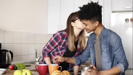 Cute-innocent-caucasian-girl-with-hipster-glasses-kissing-her-mulatto-boyfriend-on-the-cheek.-Having-lunch,-spending-time-together.-Couple,-relationship-goals,-romantic-commitment.