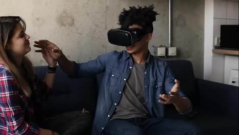 Young-guy-experiencing-virtual-reality-game-with-his-girlfriend-helping-him.