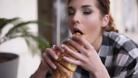 Slow-motion-of-a-seductive-girl-takes-a-croissant-in-her-hands-and-gently-bites-it-with-her-eyes-closed-in-pleasure.-Wiggle-with-enjoyment-and-taste.-Close-up
