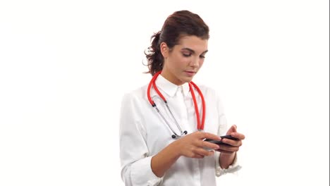 Portrait-of-a-young-nurse-using-her-smartphone-to-text-messages.-Young-medical-professional-with-stethoscope-and-lab-coat-isolated-on-white-background