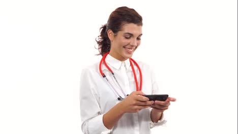 Porträt-Einer-Jungen-Lächelnden-Krankenschwester,-Die-Ihr-Smartphone-Zum-Senden-Von-Textnachrichten-Nutzt.-Junger-Mediziner-Mit-Stethoskop-Und-Laborkittel-Isoliert-Auf-Weißem-Hintergrund