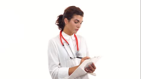 Friendly-young-female-doctor-reviews-and-writes-notes-on-a-clipboard.-Portrait-of-young-medical-professional-with-stethoscope-and-lab-coat-isolated-on-white-background