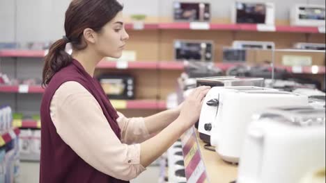 Young-female-costumer-choosing-new-toster-in-appliance-store.-Looking-for-kitchenware.