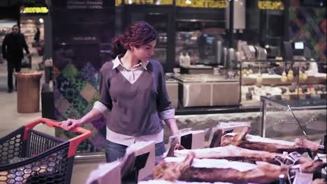 Young-female-buyer-picks-out-some-pre-packed-meat-product-in-a-grocery-store