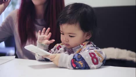 An-adorable-cute-asian-toddler-boy-is-playing-games-on-cellphone.