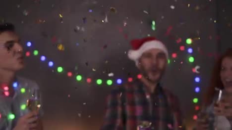 Group-of-friends-celebrating-enjoying-new-years-eve-party-having-fun-celebration.-Friendly-and-joy.-Happy-emotion.-Christmas-decorations-at-home.-Man-exploding-confetti-stick,-clinking-glasses-with-champagne