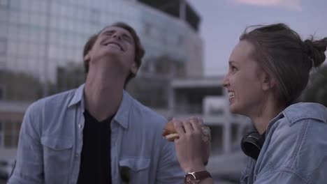 Happy,-young-couple-are-hanging-out-in-the-park.-Lauging-and-smiling.-Girl-is-eating-burger.-The-young-guy-gently-wipes-the-sauce-off-his-girl's-lips-and-licks-a-finger.-Close-up
