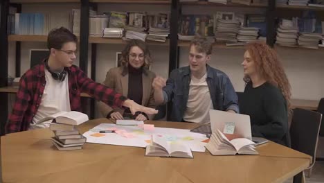 European-happy-team-of-business-people-or-students-stack-hands-in-pile-together-as-teamwork-and-help,-friendship-concept,-support-in-group-work,-unity-trust-cooperation.-Front-footage.-Slow-motion.-Book-shelf-on-a-background