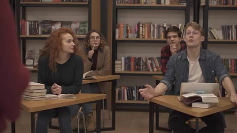 European-college-university-students-group-study-together-prepare-project-make-notes,-happy-young-people-classmates-sitting-at-the-separated-tables-and-discussing-something,-looking-at-the-camera