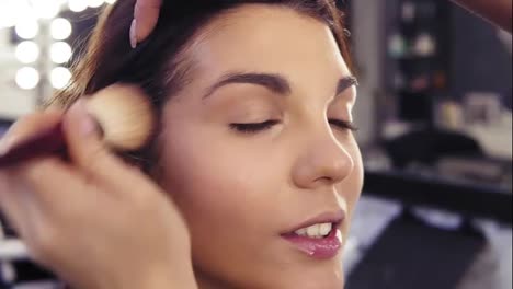 Applying-dry-foundation-or-powder-with-a-special-powder-brush.-Attractive-young-brunette-girl's-face-close-up.