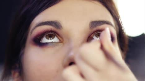Adding-some-gold-pigmented-eyeshadow-in-inner-corner-of-beautiful-brunette-girl's-eyes.-Creating-flawless-colorful-smokey-make-up-look.-Make-up-artist-craft.