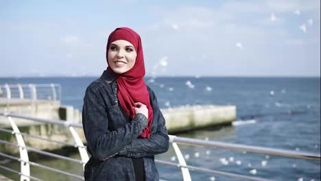 Junges-Muslimisches-Mädchen-Genießt-Einen-Spaziergang-Am-Meer-Mit-Fliegenden-Möwen-Im-Hintergrund