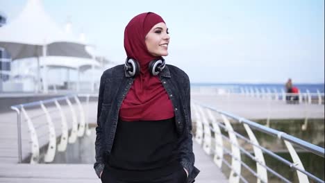 Slow-motion-outdoors-footage-of-a-young-muslim-girl-having-a-walk-near-the-sea-side,-enjoying-her-free-time