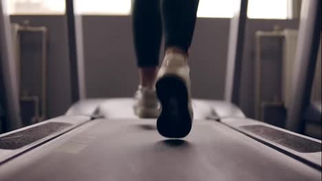 Slow-motion-footage-of-supposedly-female-legs-in-sneakers-running-on-treadmill.