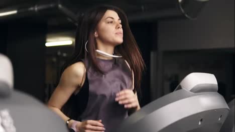 Attractive-brunette-girl-with-long-hair-in-her-20's-wearing-dryfit-sportswear,-running-on-treadmill.