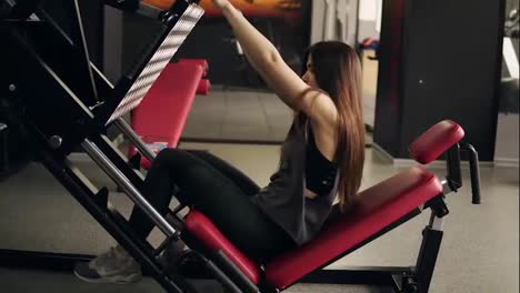Sportive-attractive-brunette-gitl-in-her-20's-working-out-on-leg-press-mashine-at-the-gym.