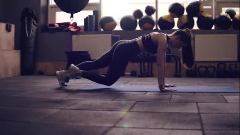 Plank-with-leg-twists-workout-performed-by-attractive-athletic-brunette-female-in-her-20's.-Indoors-slow-motion-footage.