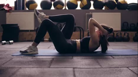 Lying-abdominal-exercises-with-leg-twists-performed-by-sportive-brunette-girl-wearing-black-sportswear.
